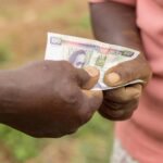 Captured moment of two individuals exchanging currency outdoors in Kenya.